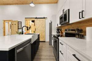 Custom kitchen in Red River Gorge cabin with white cabinets and barn door, showcasing our construction quality.