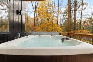 Hot tub on a cabin deck overlooking a fall forest in Kentucky. Relaxing retreat in nature, perfect for a custom built cabin getaway with our construction company in the Red River Gorge.