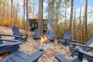 Cozy cabin fire pit with blue Adirondack chairs in a circle, inviting gathering. Cabin building company crafted this idyllic Kentucky scene.
