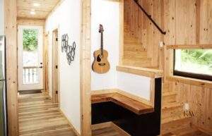 Cozy cabin interior with wood paneling, stairs, and a guitar hanging on the wall. A custom-built home detail showcasing quality construction and craftsmanship.