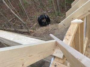 Cabin construction in the Red River Gorge, Kentucky. Unfinished wooden framework of a custom built home overlooks a wooded area with a tire swing. Build your dream cabin with our company.