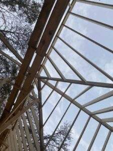 Cabin construction frame against a blue sky, showcasing the intricate wooden beams and supports. A testament to building with our Kentucky cabin building company in the Red River Gorge.