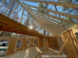 Framing of a custom built home under construction, showcasing the roof trusses and wall studs. Natural light streams through the incomplete structure, emphasizing the craftsmanship of this cabin building company in Kentucky.